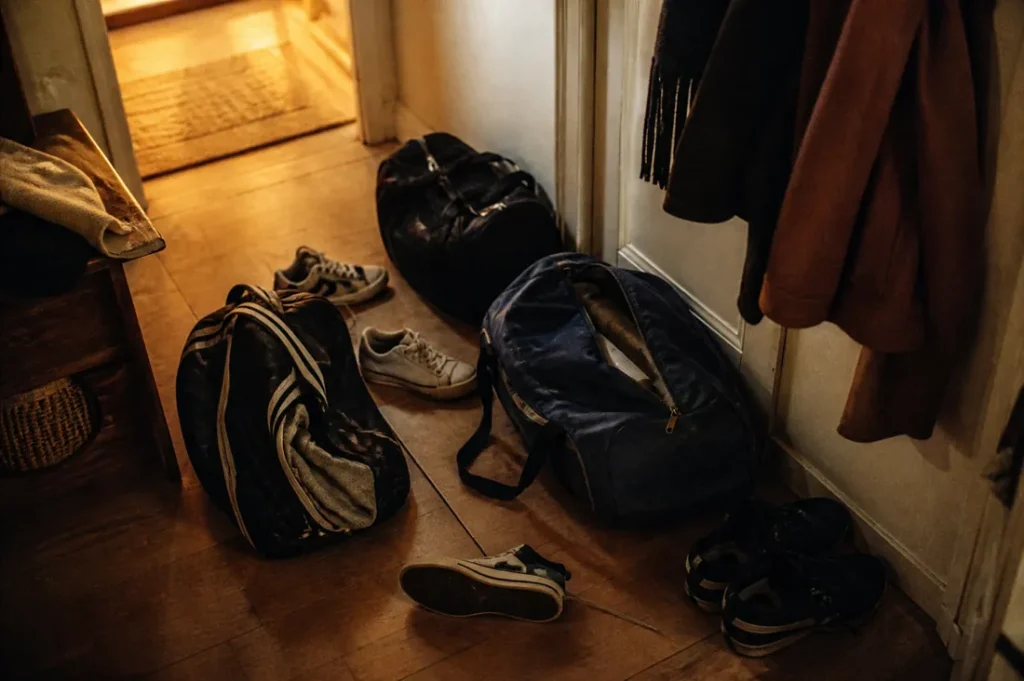 ce qu'on transmet vraiment à ses enfants sacs de sport dans une entrée chaussures éparpillées trace de vie familiale transmission invisible parentalité