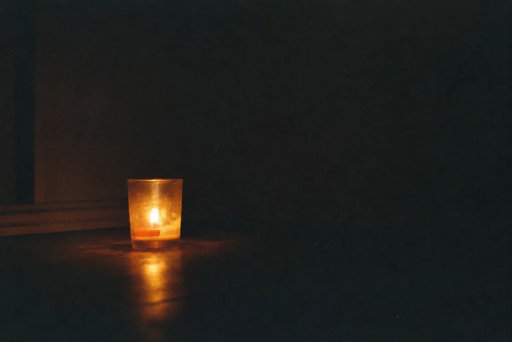 Bougie seule dans une pièce sombre et ordinaire, lumière fragile et chaleureuse dans l’obscurité — ce que mes enfants m’ont appris